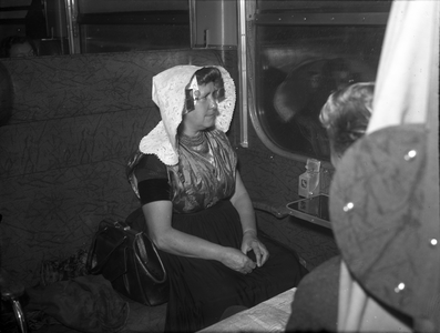 804209 Afbeelding van een vrouw in Zeeuwse klederdracht in een trein.